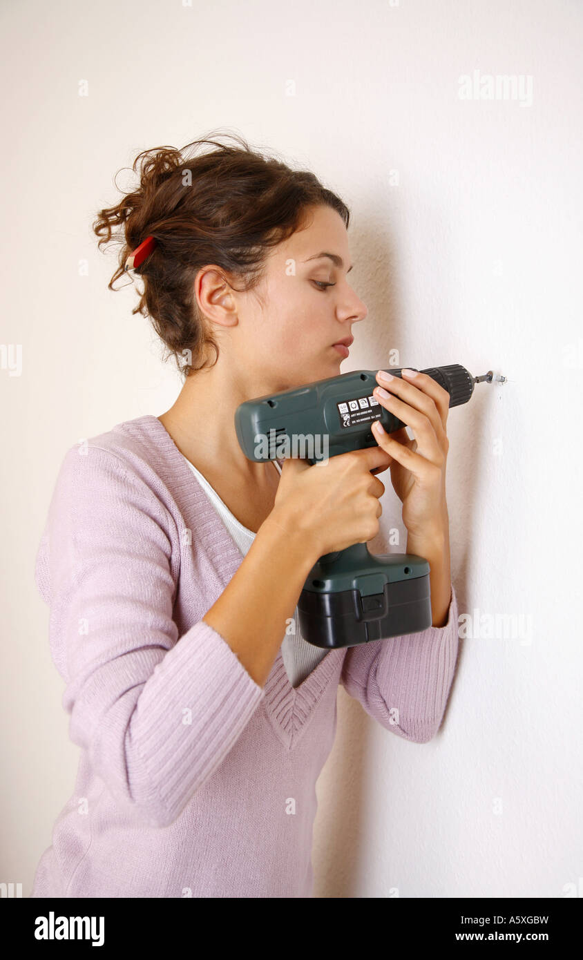 Young woman drilling in wall side view Stock Photo
