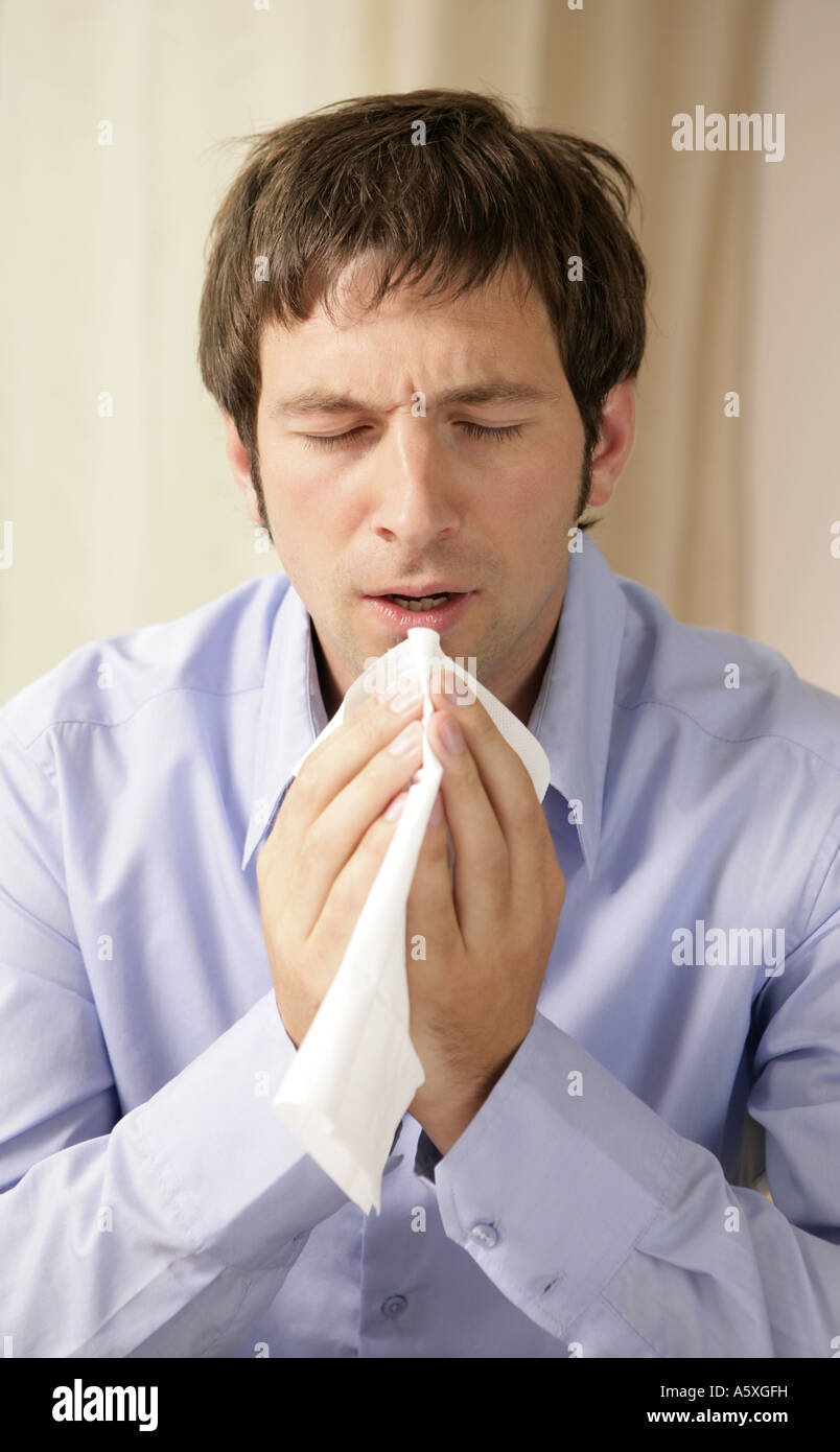 Young man sneezing close up Stock Photo