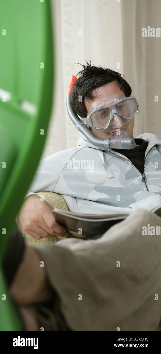 Young man wearing snorkel reading book Stock Photo