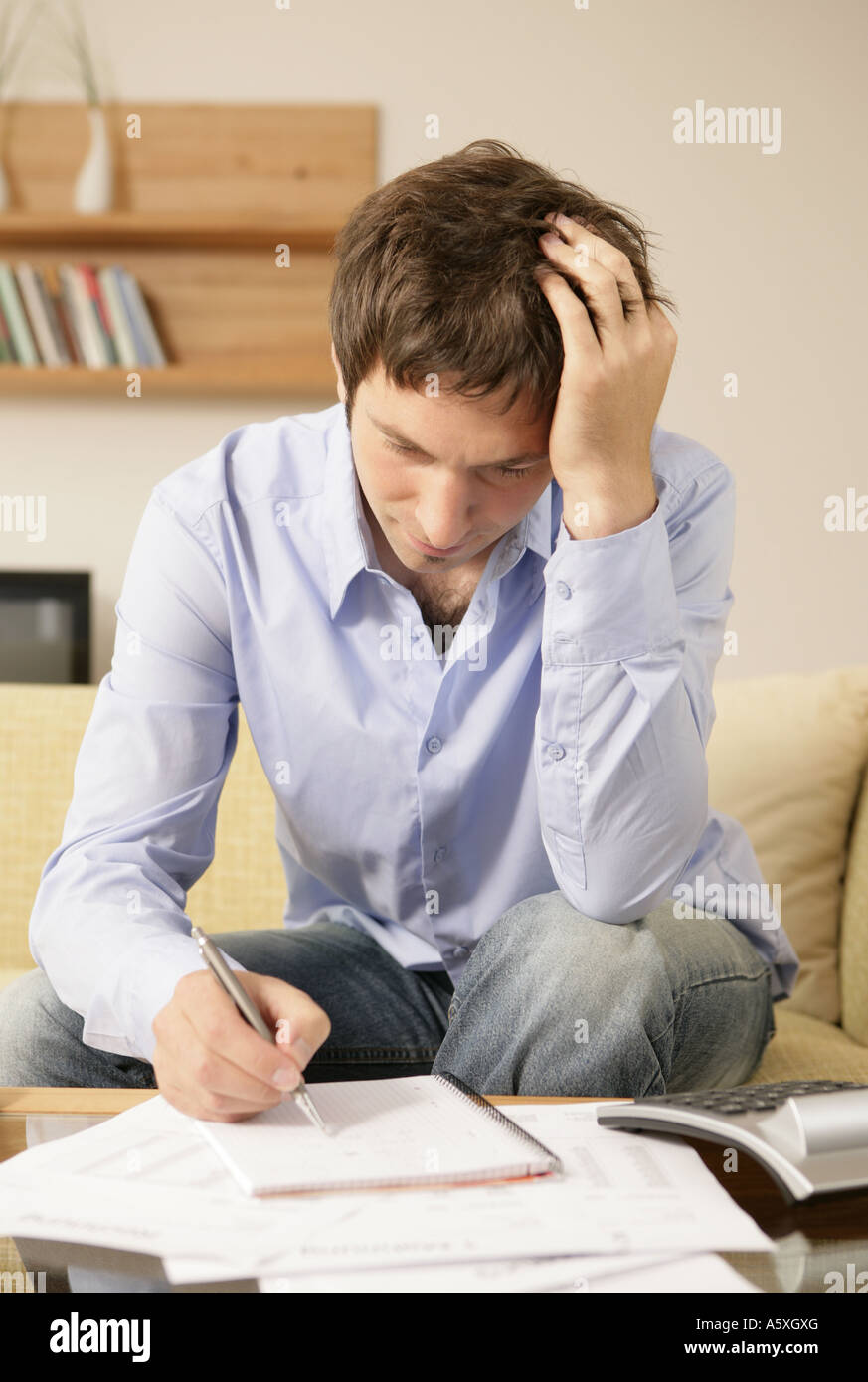 Young man writing on notepad hand in hair Stock Photo