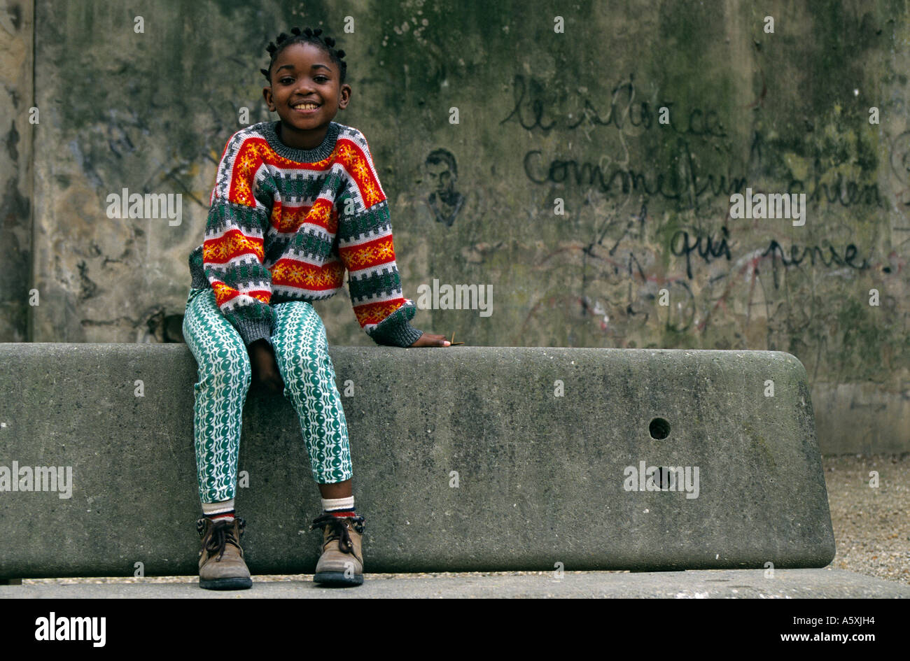 Young coloured girl sat on a bench (Bordeaux - France). Fillette de couleur assise sur un banc (Bordeaux 33000 - France). Stock Photo