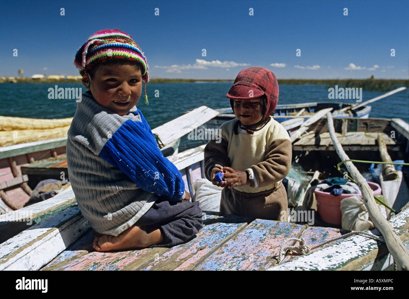 Peruvian kids on a small craft of the Lake Titicaca (Peru). Gamins sur une barque du lac Titicaca (Pérou). Stock Photo