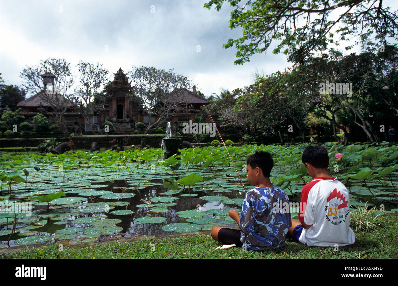 Children angling in the pond of a Balinese temple (Indonesia). Enfants pêchant dans le bassin d'un temple balinais (Indonésie) Stock Photo