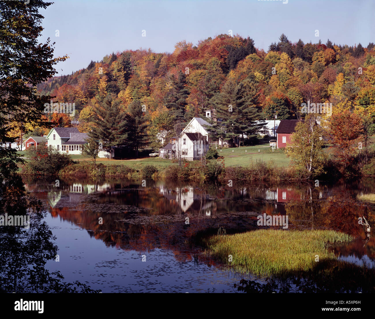 East Calais in Vermont reflects in the calm waters of a pool of water during the Autumn color season Stock Photo