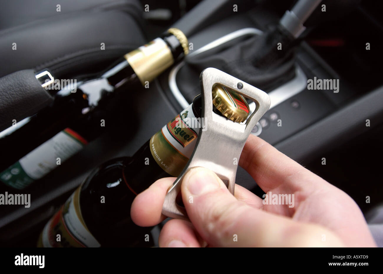 OPENING A BOTTLE OF BEER INSIDE A CAR Stock Photo