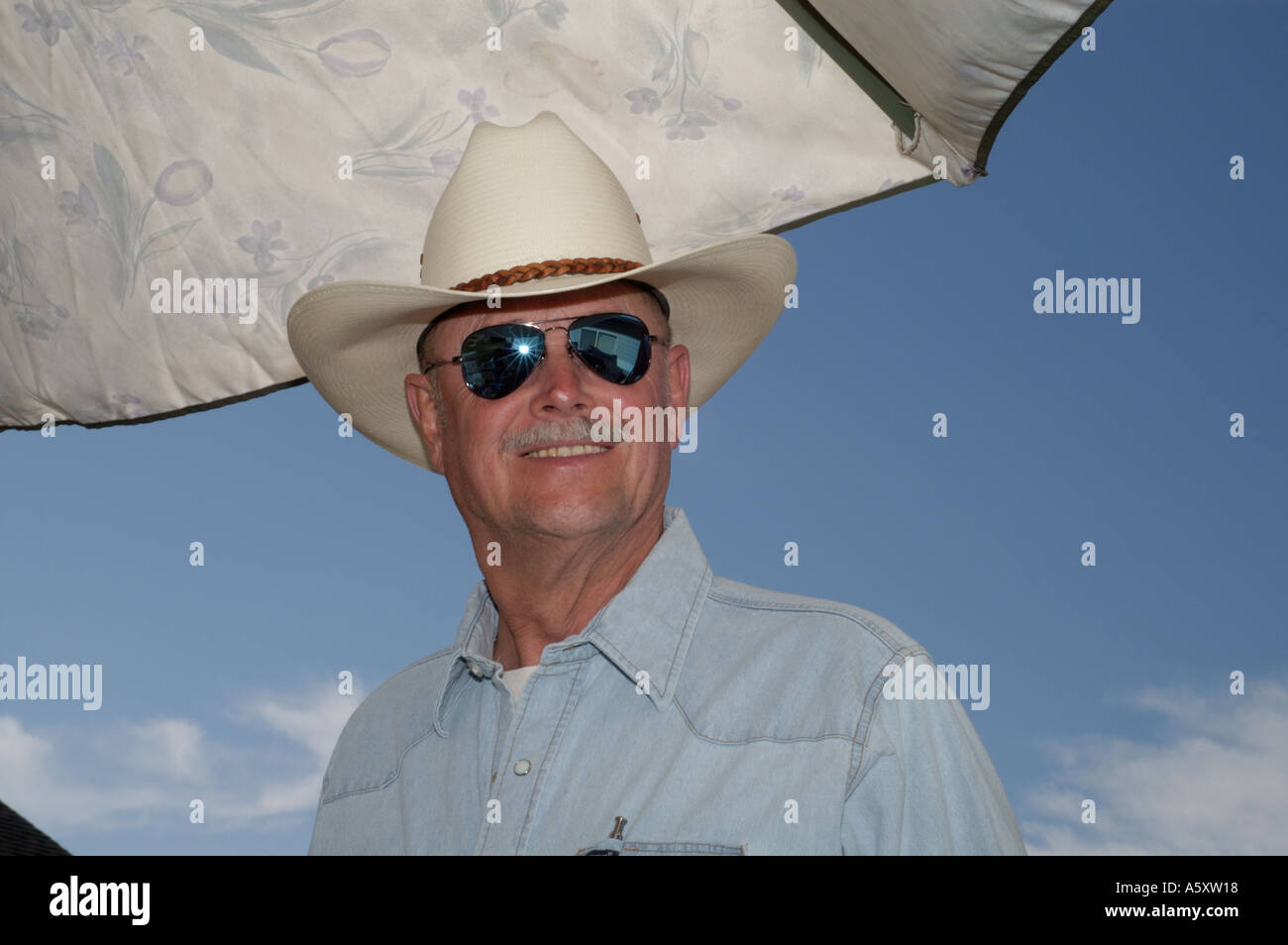 Man in sunglasses and cowboy hat against a blue sky and umbrella Stock  Photo - Alamy