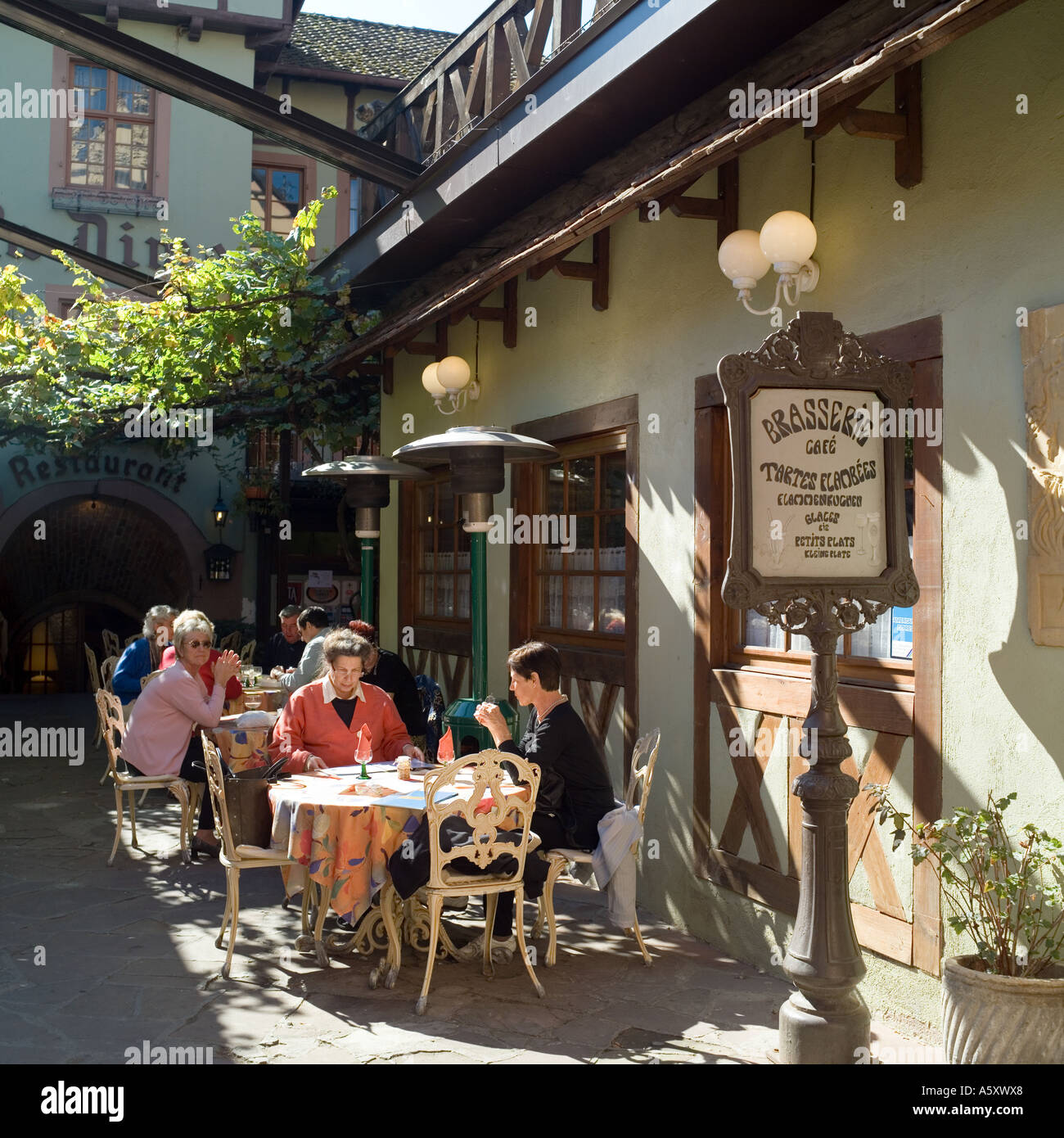 Sunny restaurant terrace in a courtyard, Riquewihr, Alsace, France Stock Photo