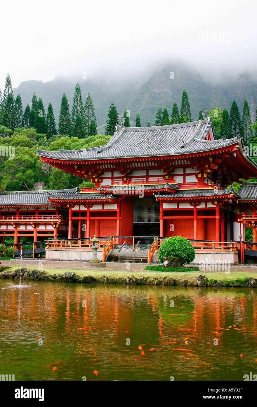 Serene pond surrounds the Asian buddhist Byodo In temple with fog shrouded mountains Valley of the temples Oahu Hawaii Stock Photo