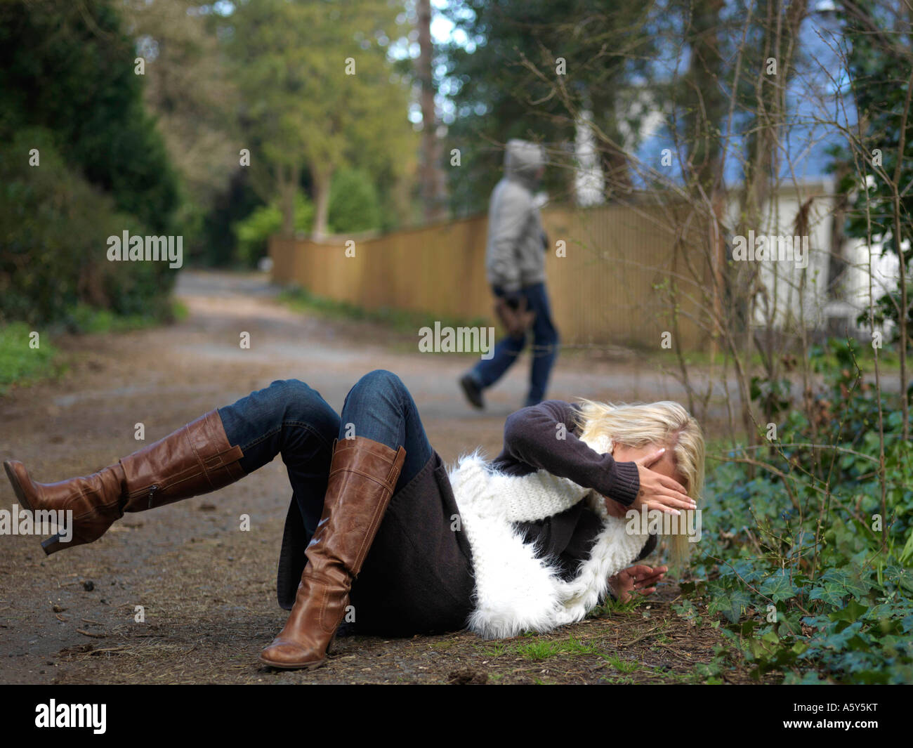 Young Woman Walking On A Quiet Public Path Being Threatened By A Mugging Robbery And The Threat Of Increasing Knife Crime By A Young Male Attacker Stock Photo