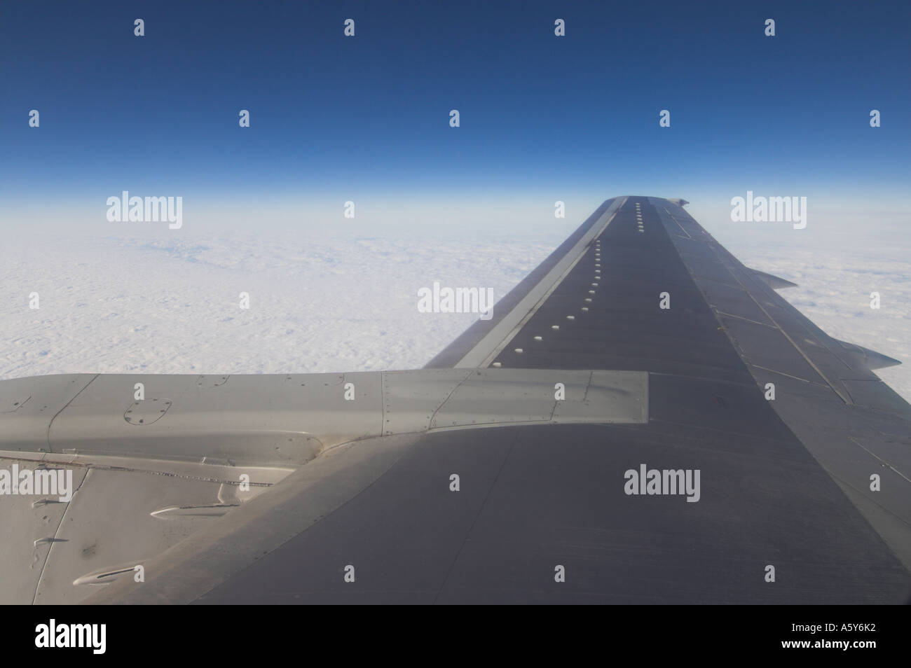 Aircraft wing taken from inside a cabin whilst flying Stock Photo