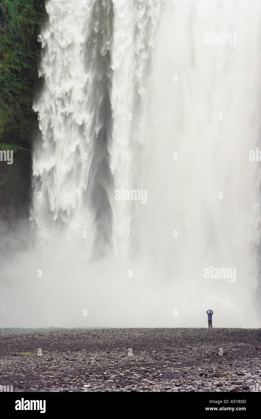 Lone Man Standing in Awe at Skogafoss Waterfall, Iceland Stock Photo