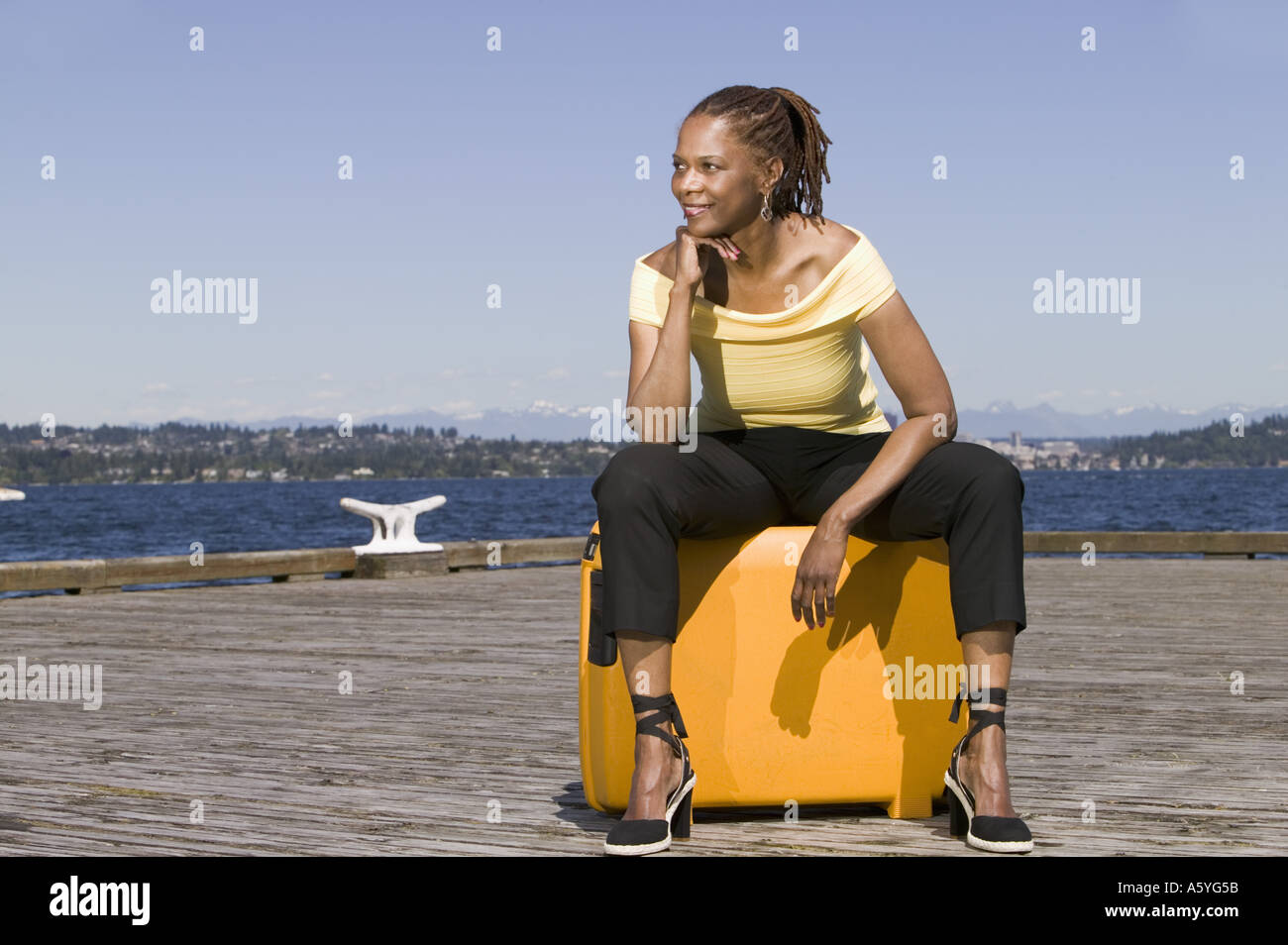 Woman outdoors sitting on suitcase Stock Photo