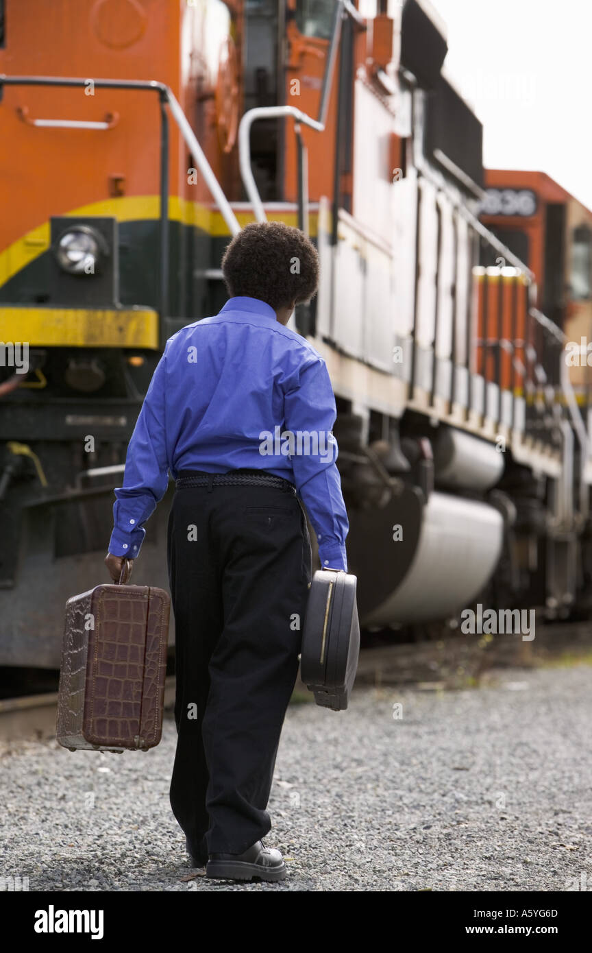 Boy walking beside train with baggage Stock Photo