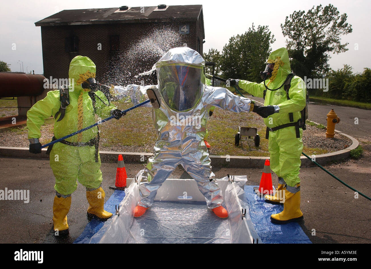Emergency workers cleaning each other off in chemical suits after bio