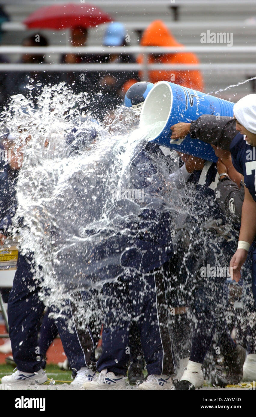 A Football coach being splashed with water as team wins championship game Stock Photo
