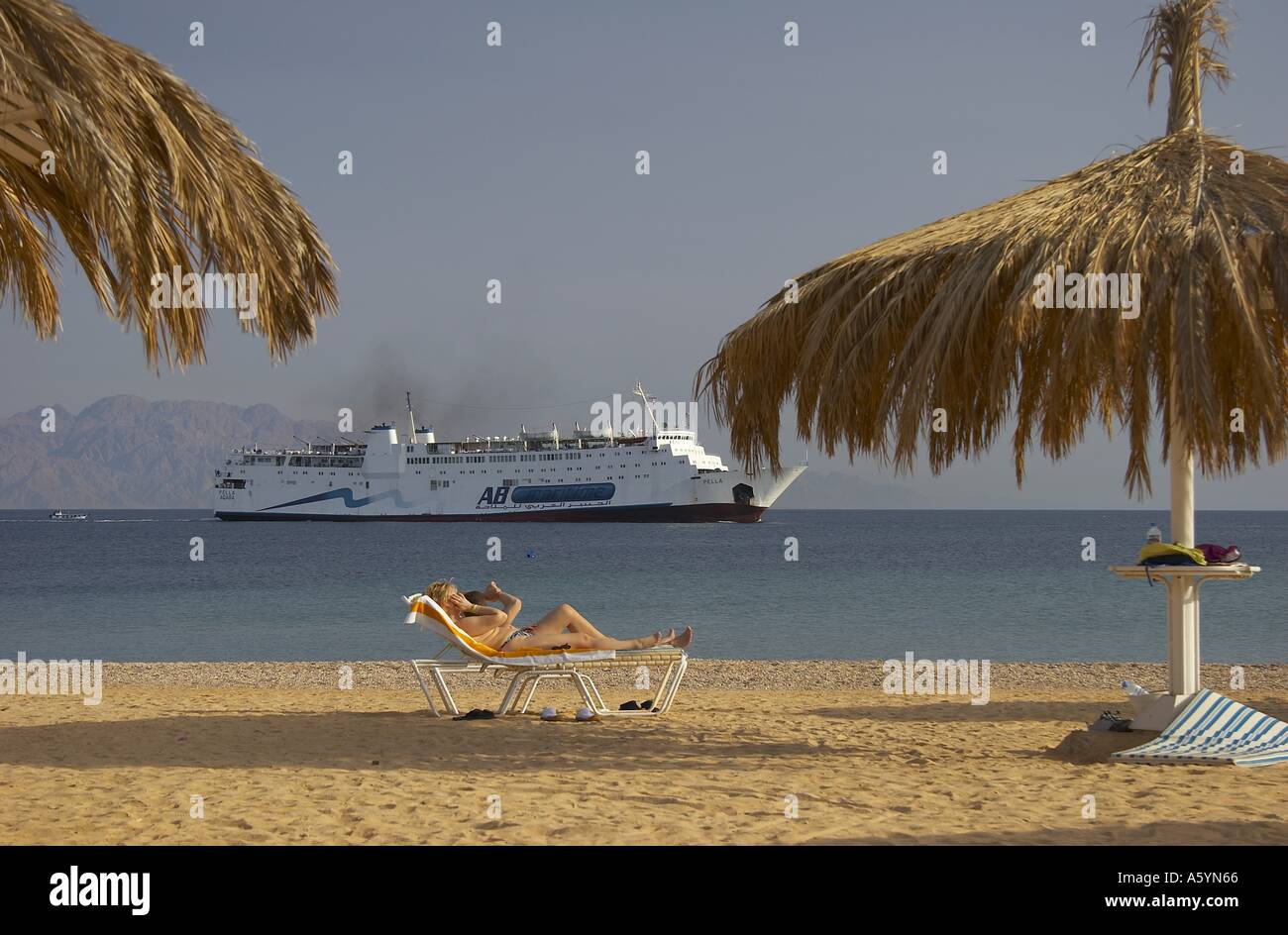 vacationers on beach / ferry in background Stock Photo