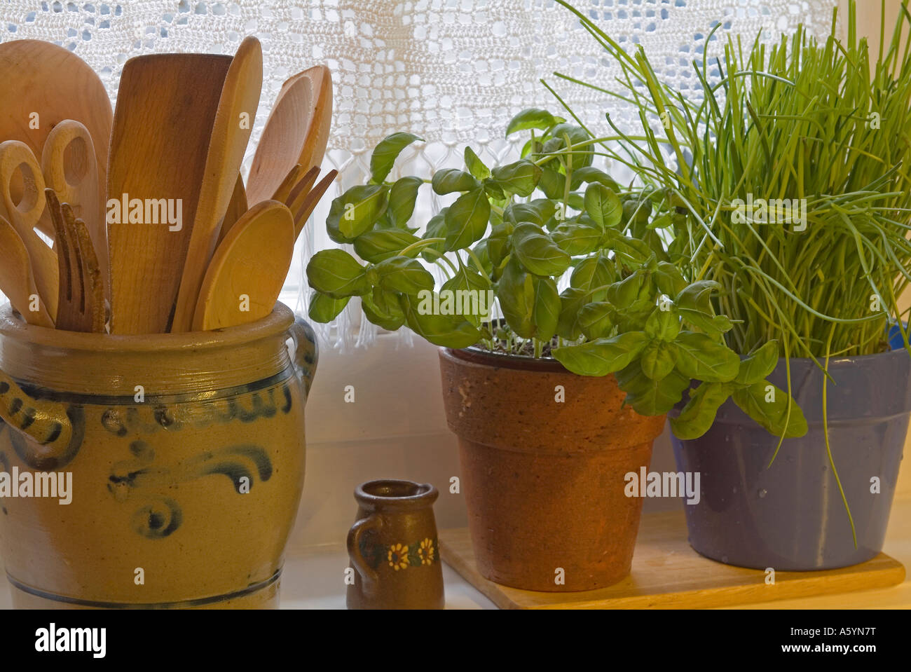 pots with herbs and wooden spoons at kitchen window Stock Photo
