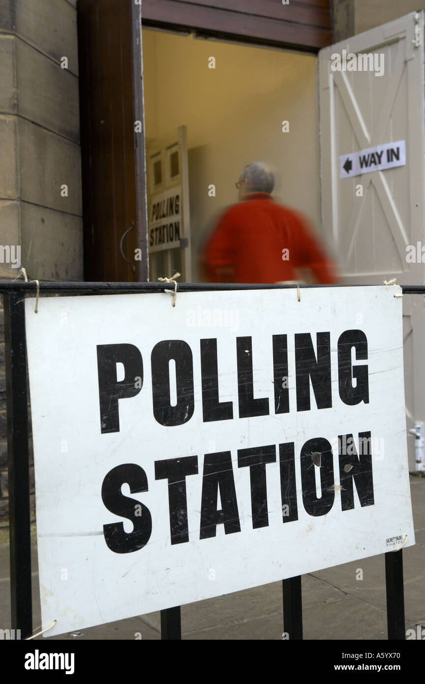 ENTRANCE TO POLLING STATION WITH MAN WEARING RED JACKET PASSING THROUGH DOOR TO CAST VOTE Stock Photo
