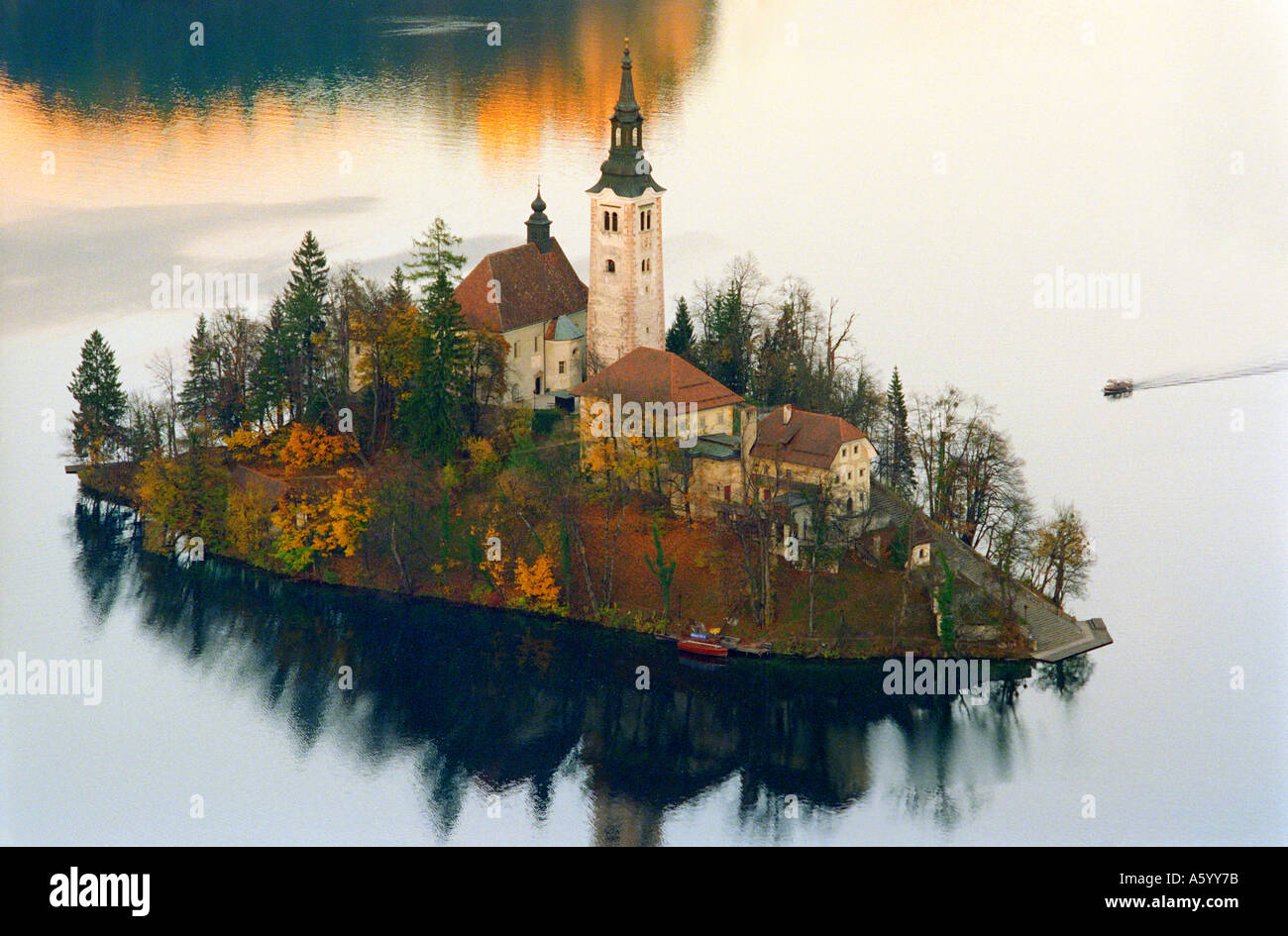 LAKE BLED ISLAND AUTUMN The church island and tourist tour boat at Lake Bled with autumnal colour Slovenia Stock Photo