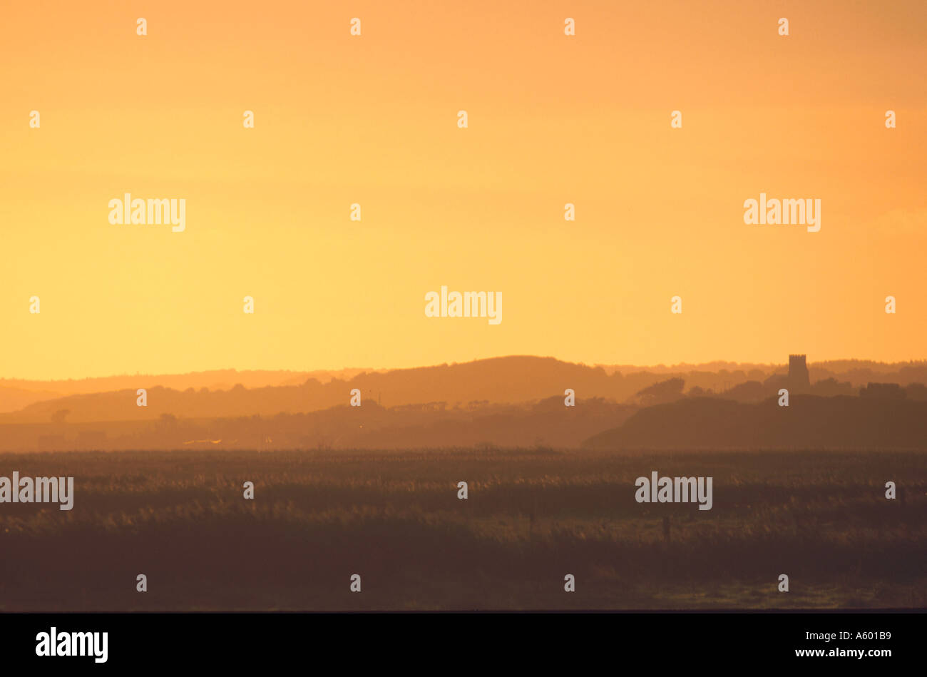 DAWN LIGHT ACROSS MARSH WITH DISTANT VIEW CHURCH TOWER AT SALTHOUSE NORTH NORFOLK EAST ANGLIA ENGLAND UK Stock Photo