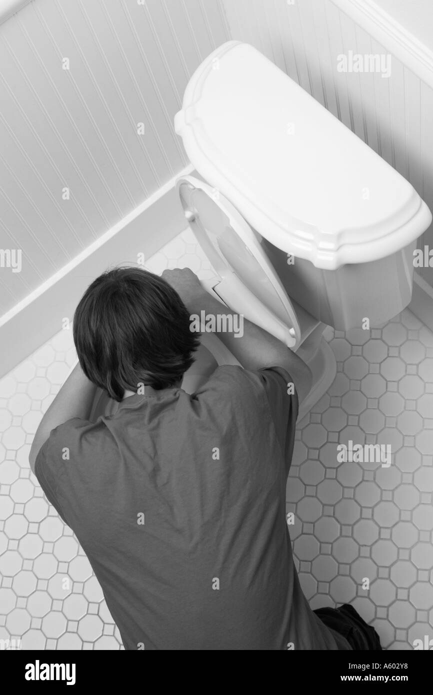 overhead view of male teenager bent over toilet being sick Stock Photo
