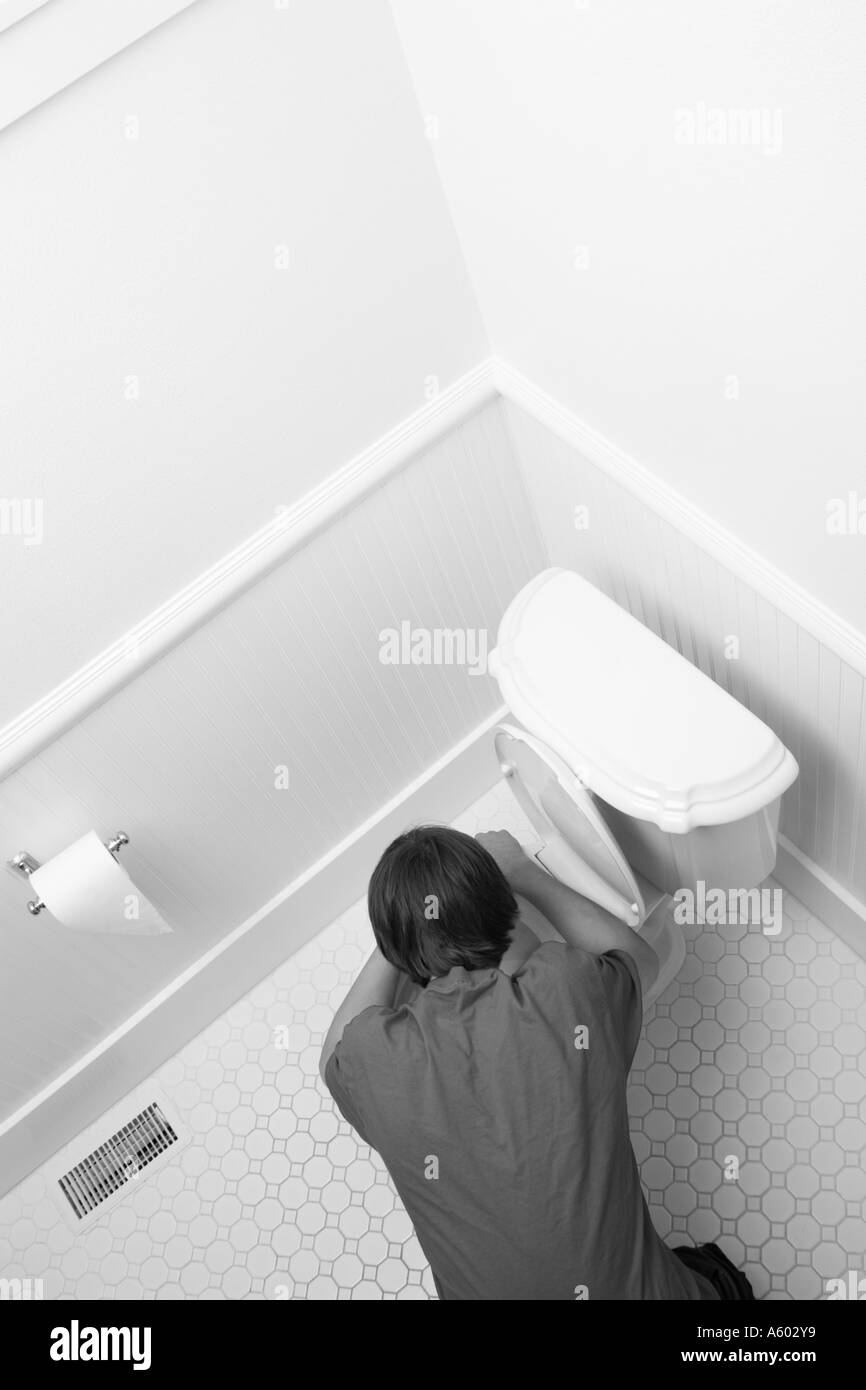 overhead view of male teenager bent over toilet being sick Stock Photo