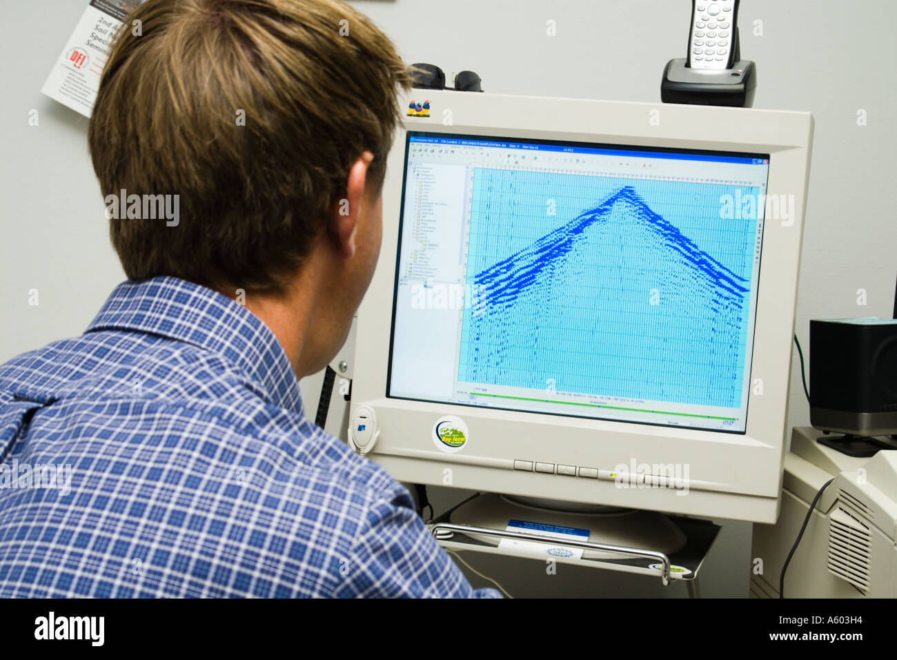 male geophysicist working at computer with seismic record on screen Stock Photo