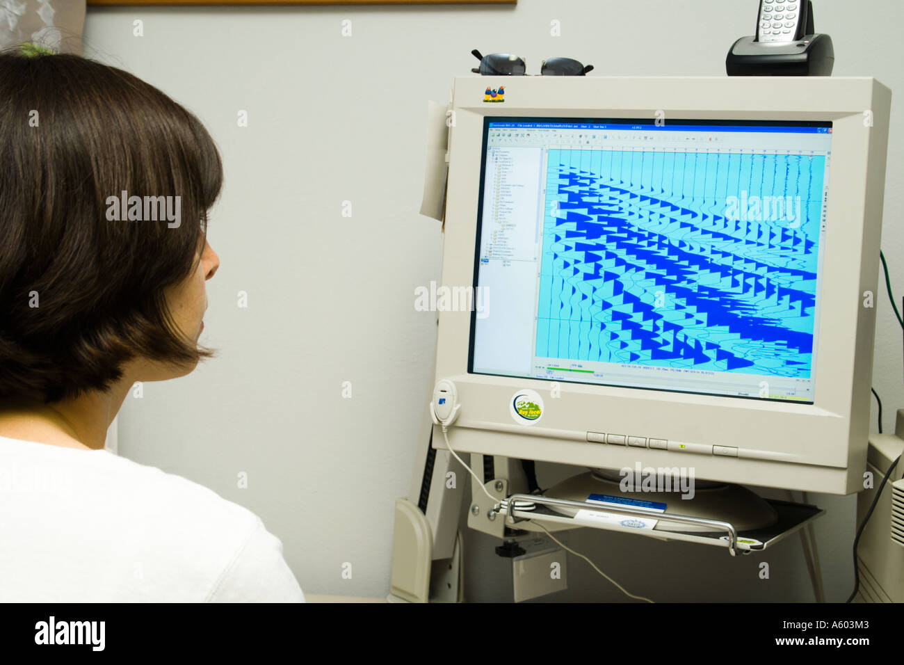 female geologist working at computer with seismic record on screen Stock Photo