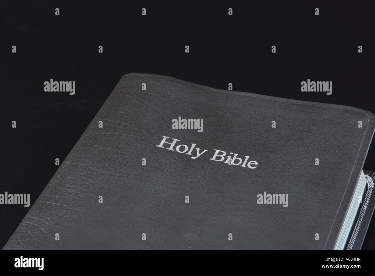 Front closeup view of Holy Bible with gray cover on black horizontal background Stock Photo