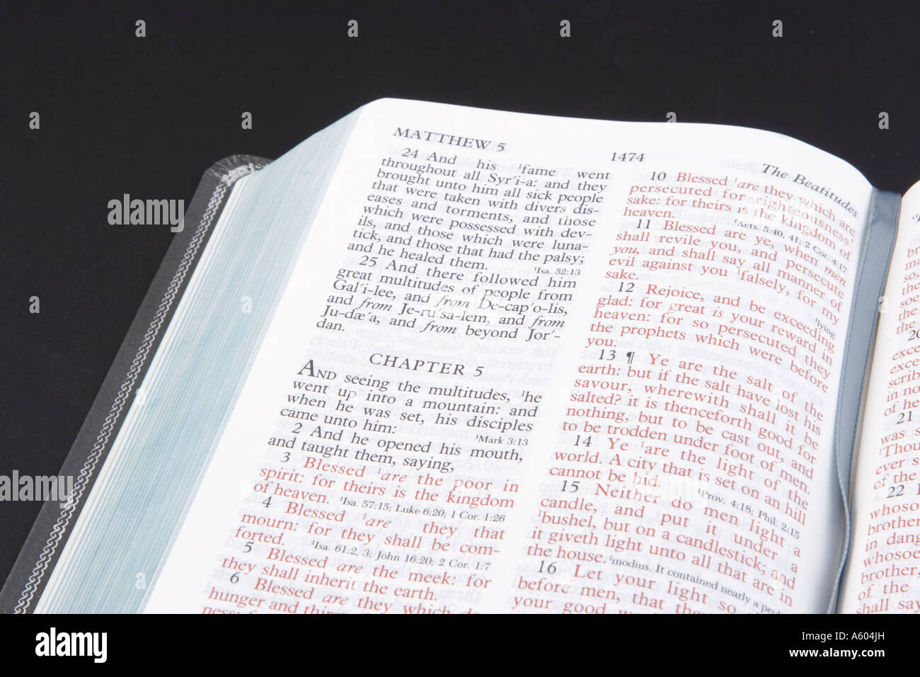 Open Holy Bible showing both black and red lettered text on black horizontal background Stock Photo