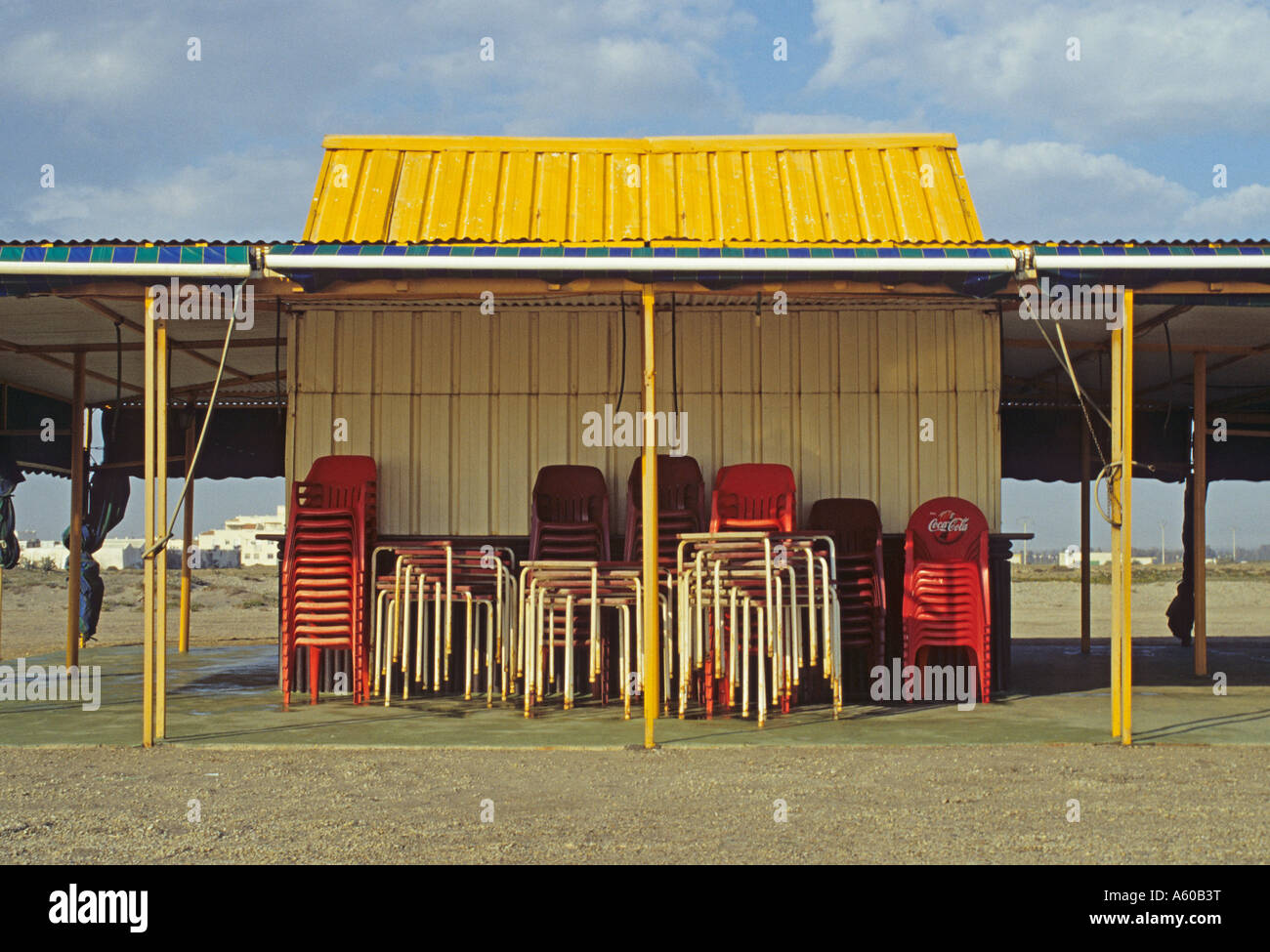 stack of chairs outside a closed kiosk on the beach at the end of the season Tarifa Andalusia Spain Stock Photo