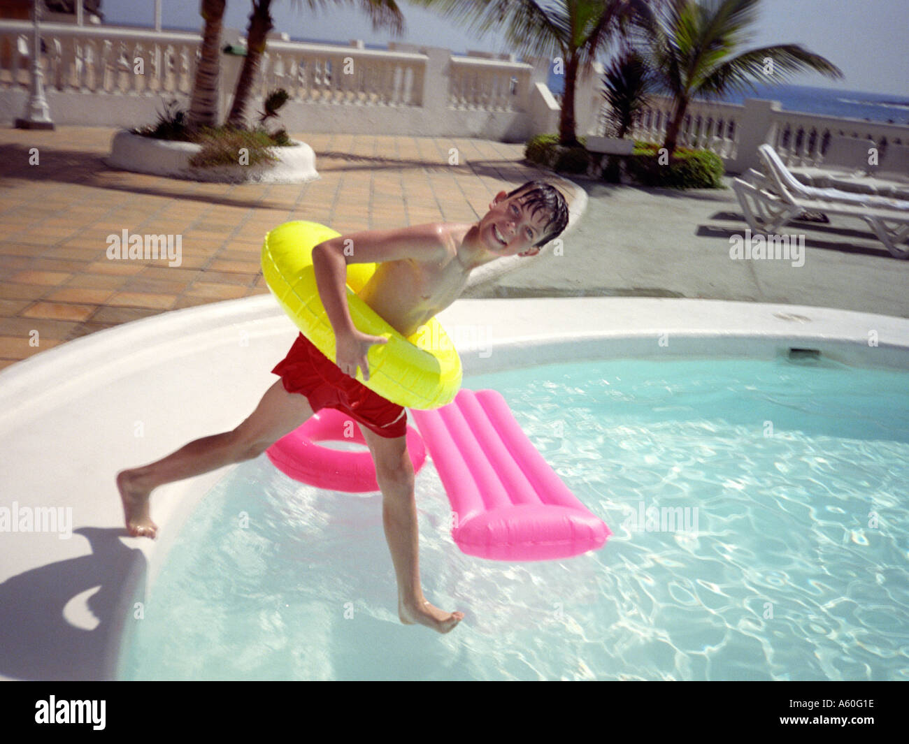 Caucasian boy having fun making fantastic jump into swimming pool at  resort. He has pose of sitting man. Back view. Stock Photo | Adobe Stock
