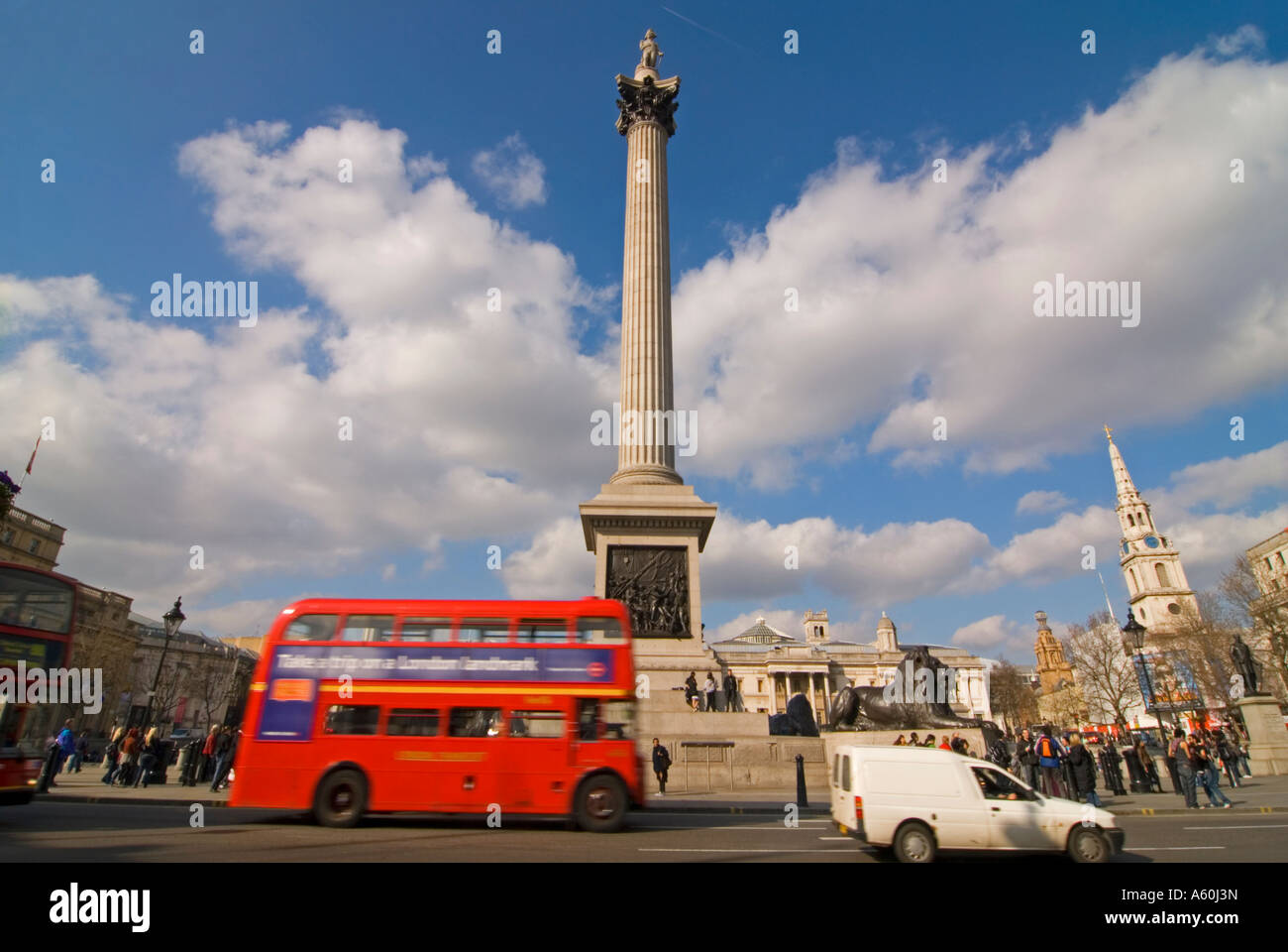 Horizontal wide angle of Trafalgar Square and Nelson's column with a Routemaster bus driving passed on a sunny day. Stock Photo