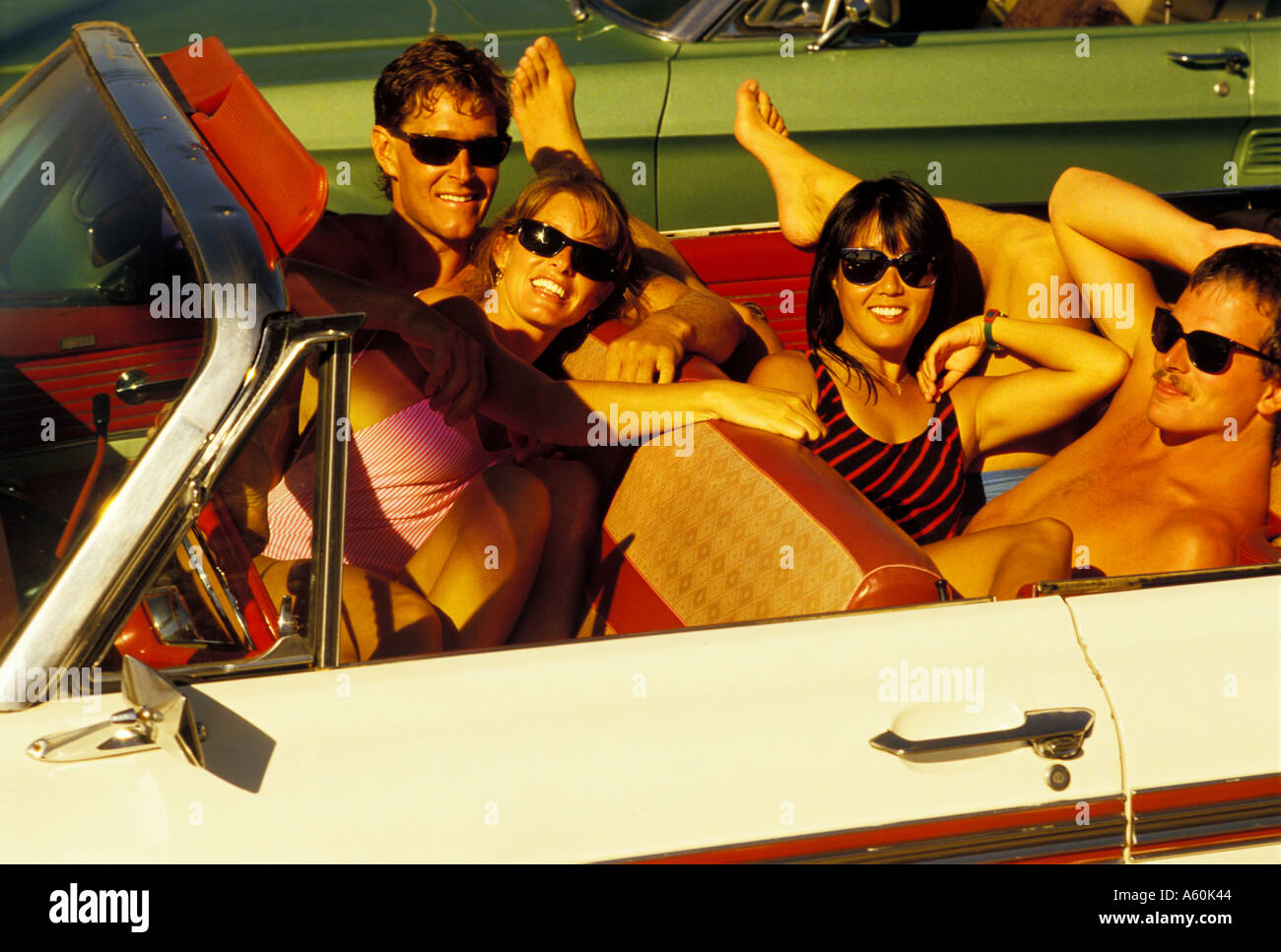 Two couples enjoy the sun at the beach in their classic convertible Stock Photo