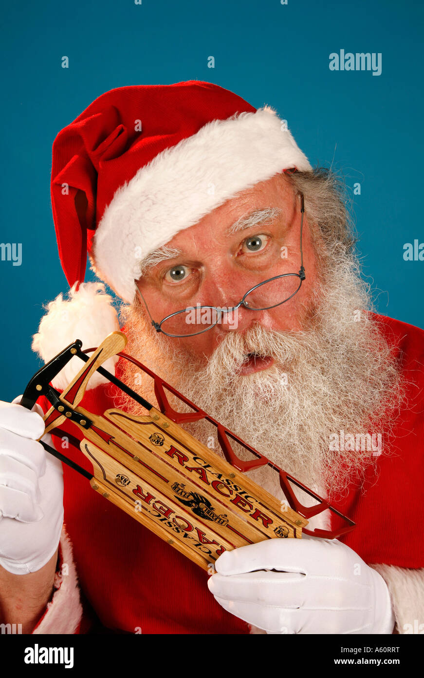 SANTA CLAUS HOLDS A SMALL RED SLED. Stock Photo