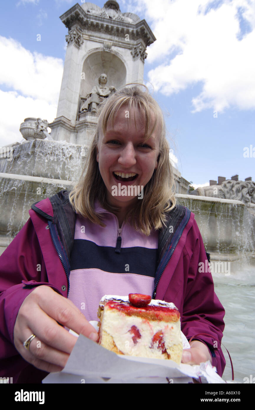 Woman laughs with glee on the receopt of a strawberry cake in Place Saint Sulpice Paris France Stock Photo
