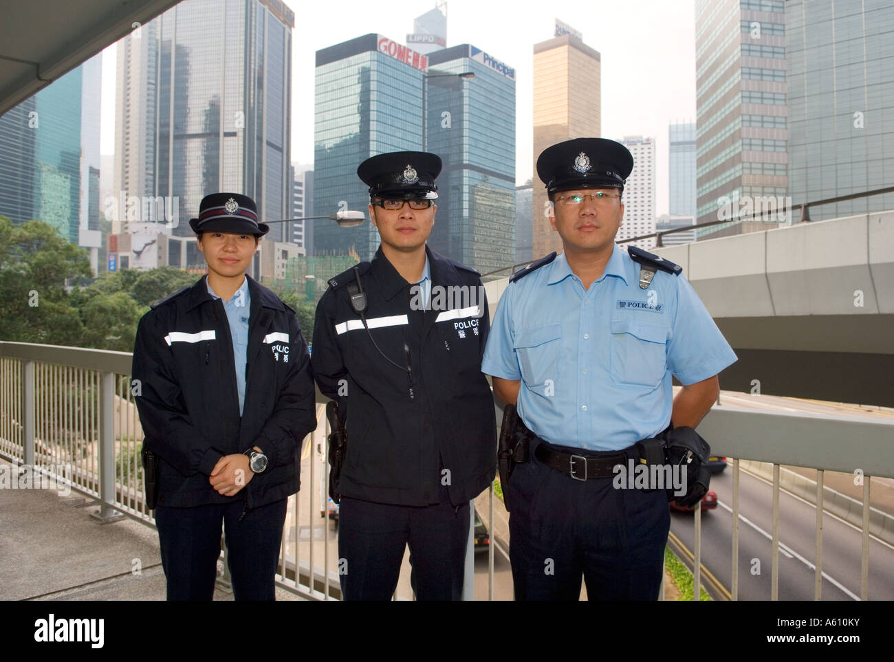 Hong Kong Island, China. Uniform police pose for photograph near Police Headquarters on Harcourt Rd. Admiralty District backdrop Stock Photo