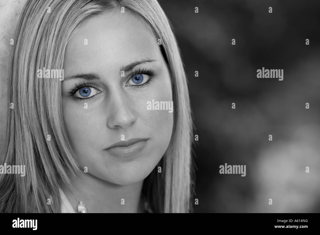 Black and white shot of a beautiful young woman with bright blue eyes and an enigmatic smile Stock Photo