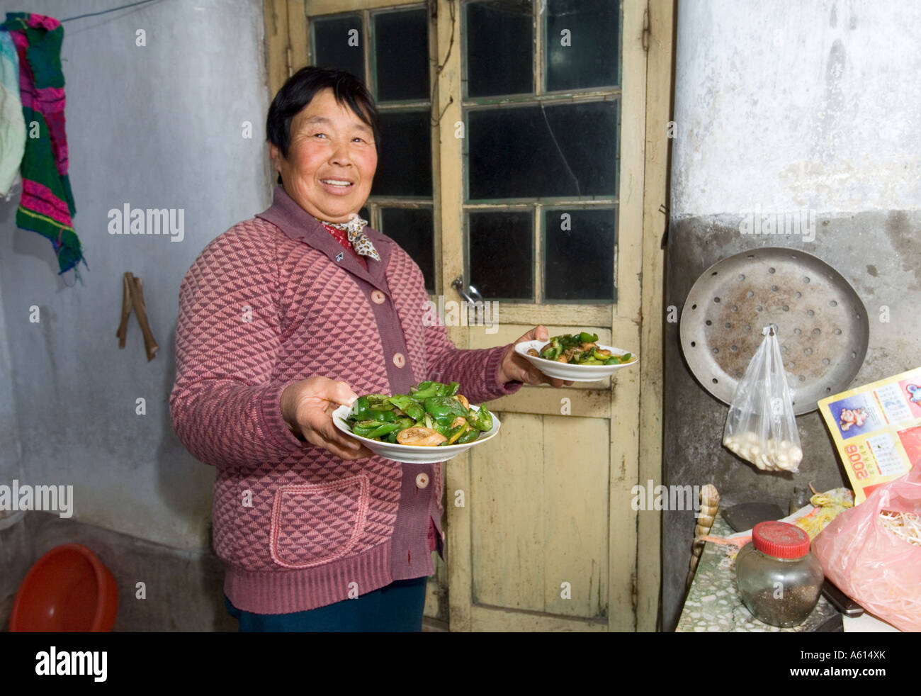 Farmer's wife holding cooked vegetable meal in farmhouse kitchen in village of Poli near Penglai, Shandong Province, China Stock Photo