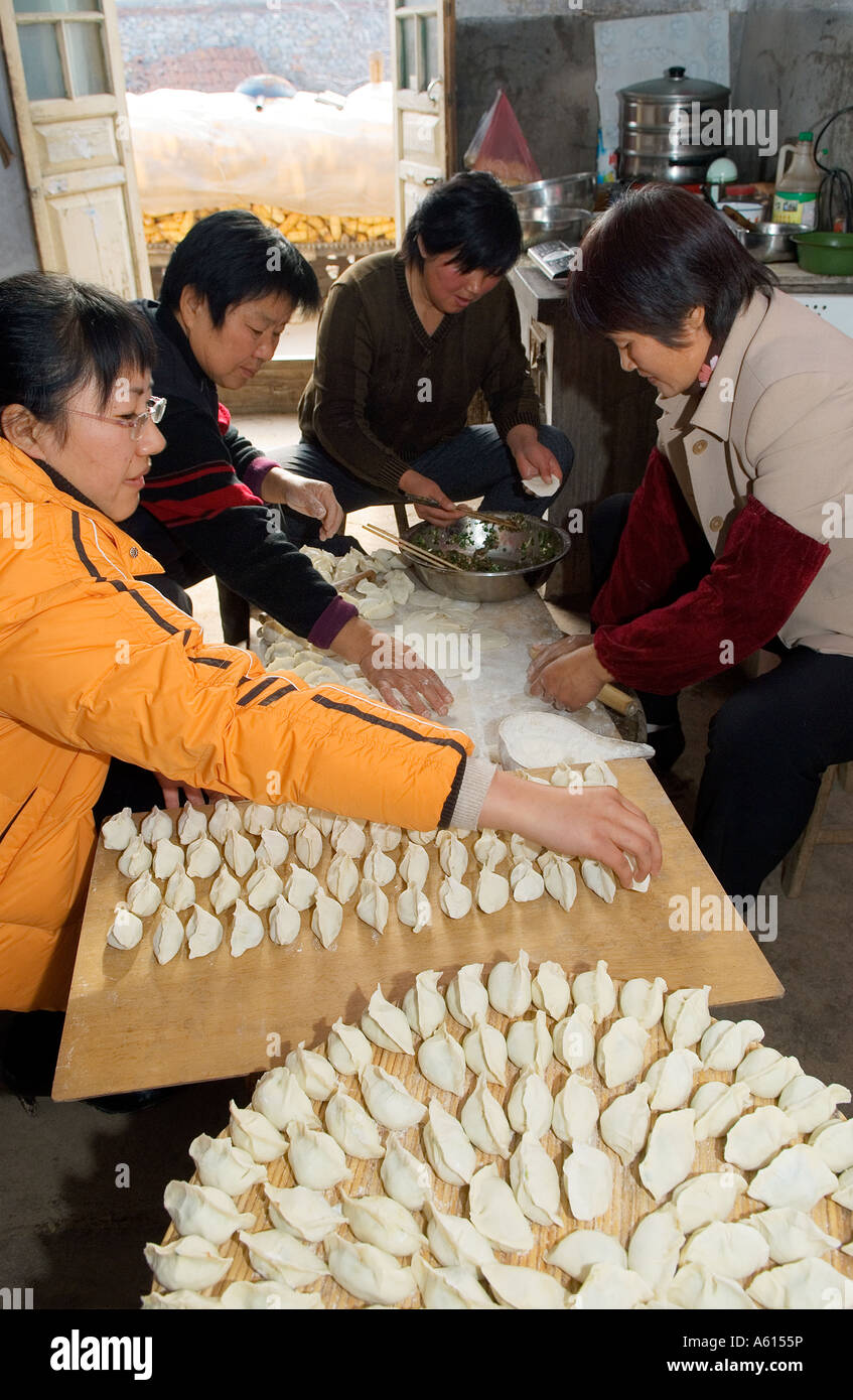 Women making preparing traditional dim sum Chinese dumplings in farmhouse kitchen, Shandong Province, China Stock Photo