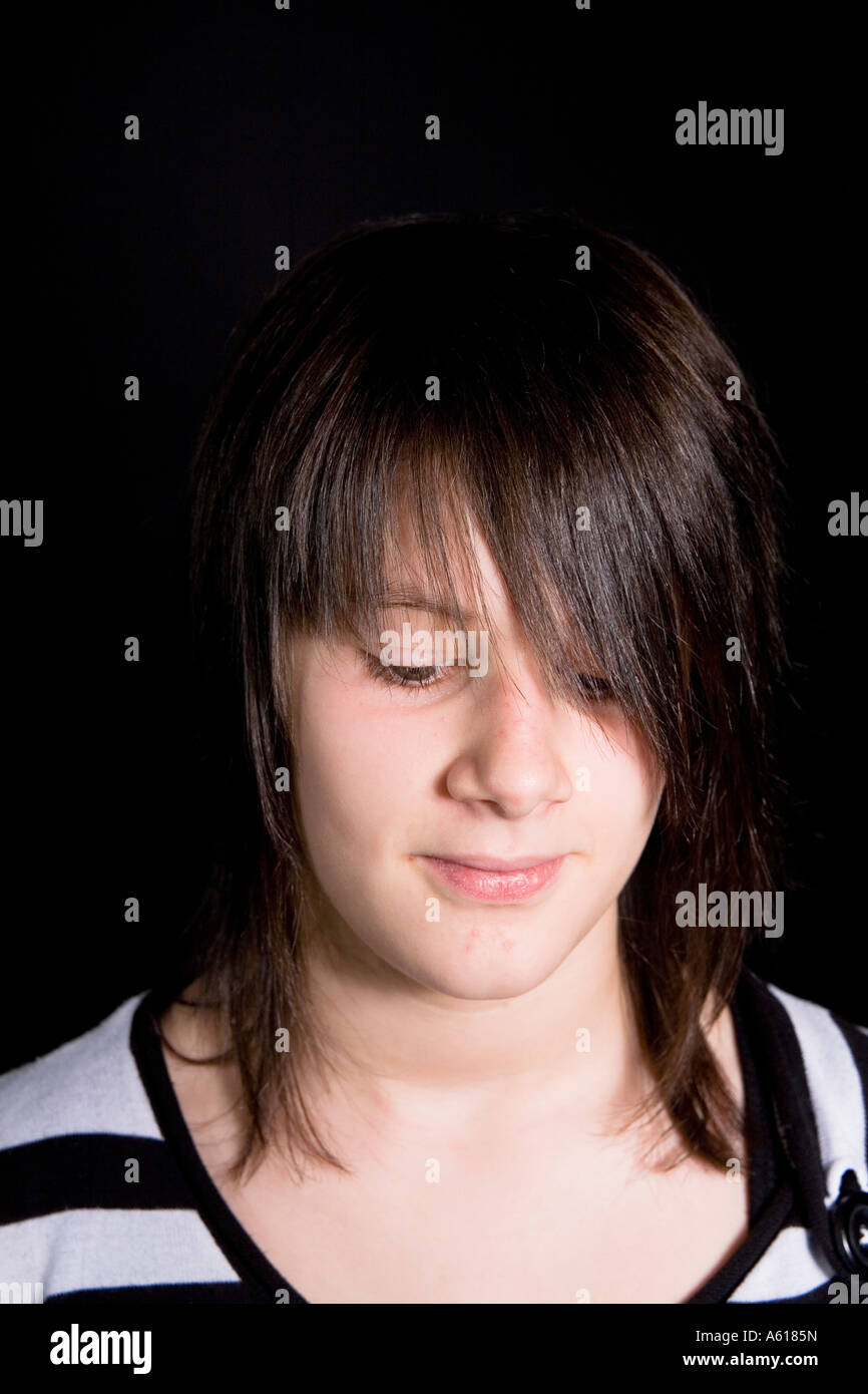 Young girl looks downwards with embarrassed smile Stock Photo