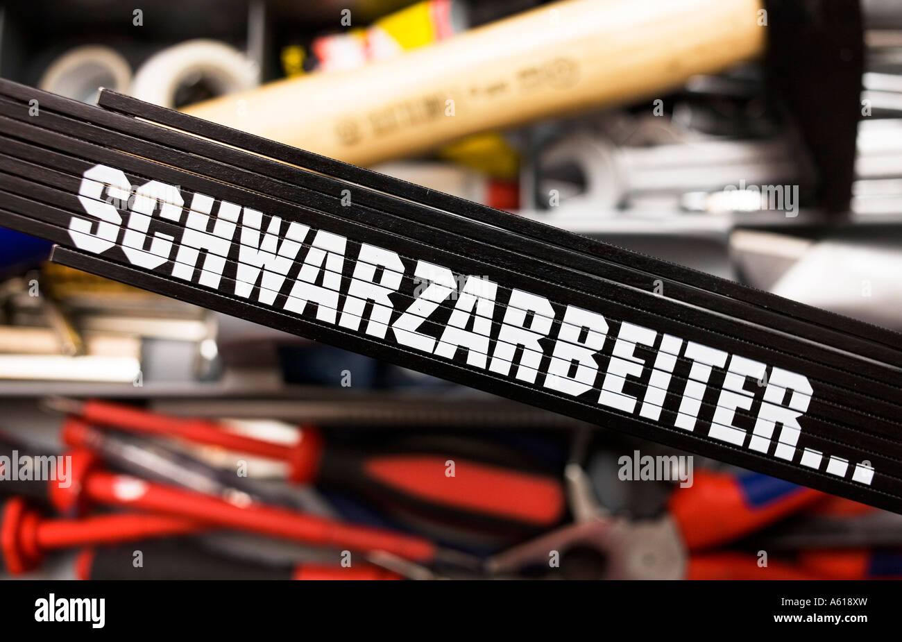 Black folding rule with writing 'schwarzarbeiter' in front of a tool box Stock Photo