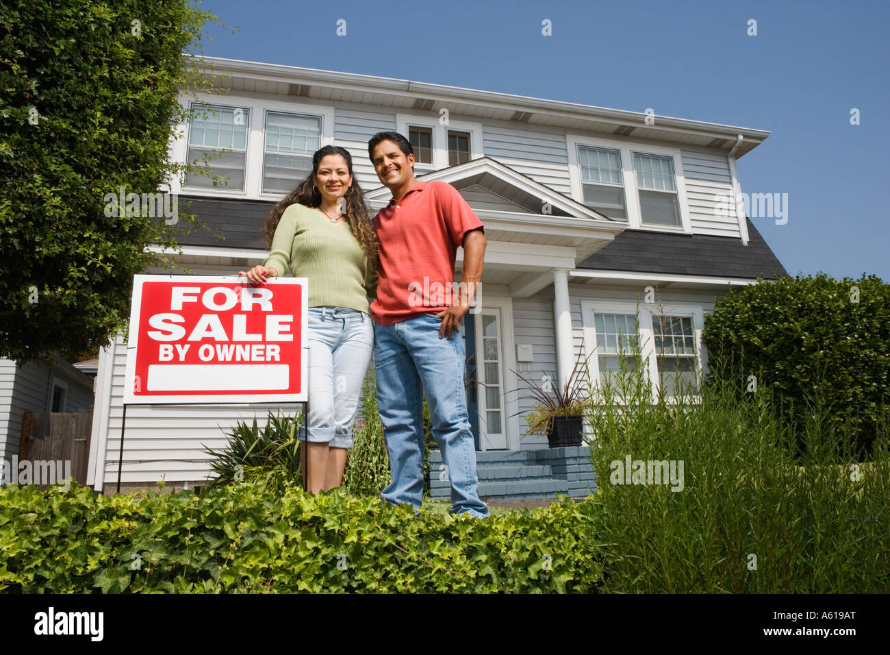 Hispanic couple with For Sale sign in front of house Stock Photo - Alamy