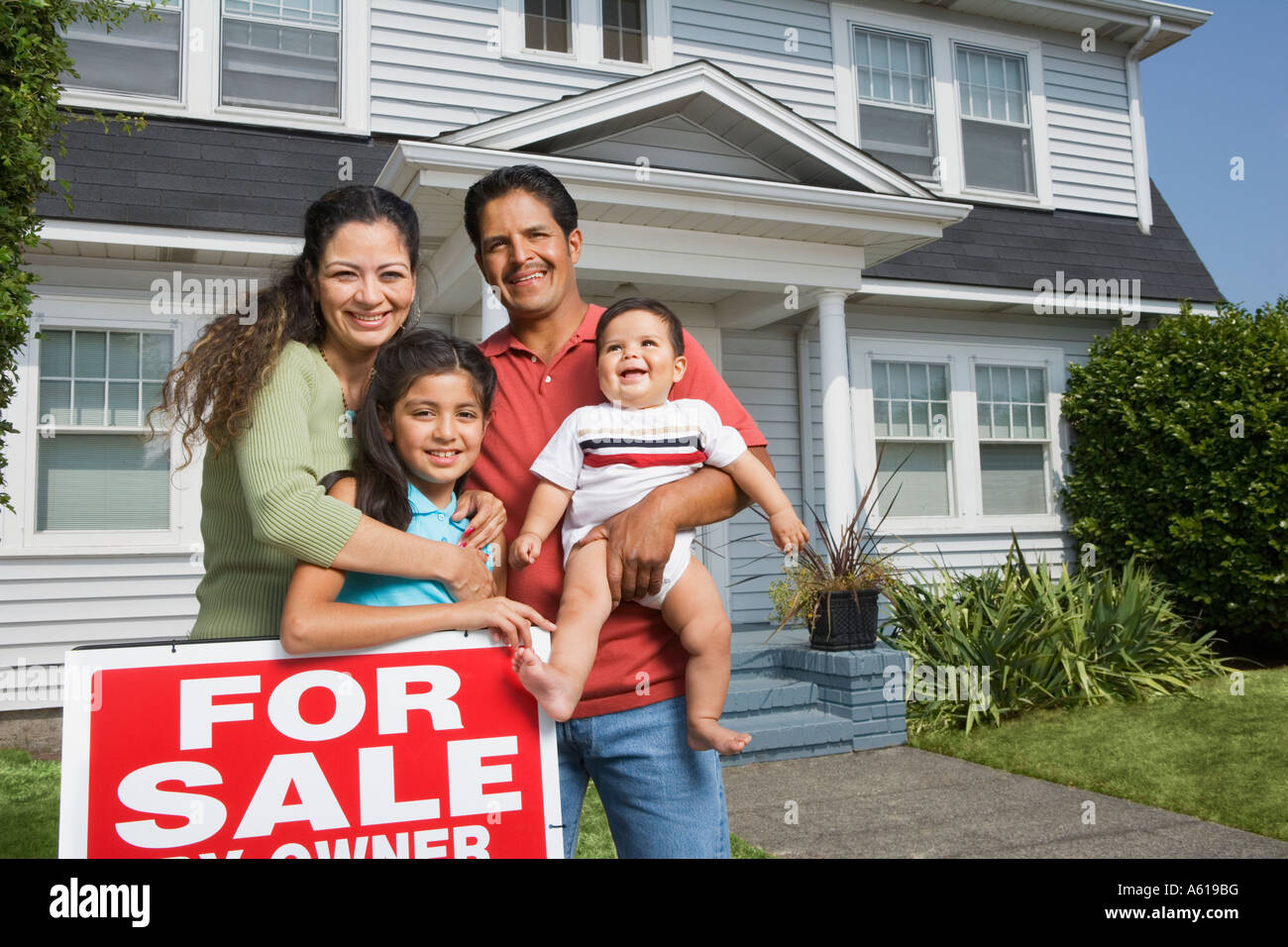 Hispanic family with For Sale sign in front of house Stock Photo - Alamy