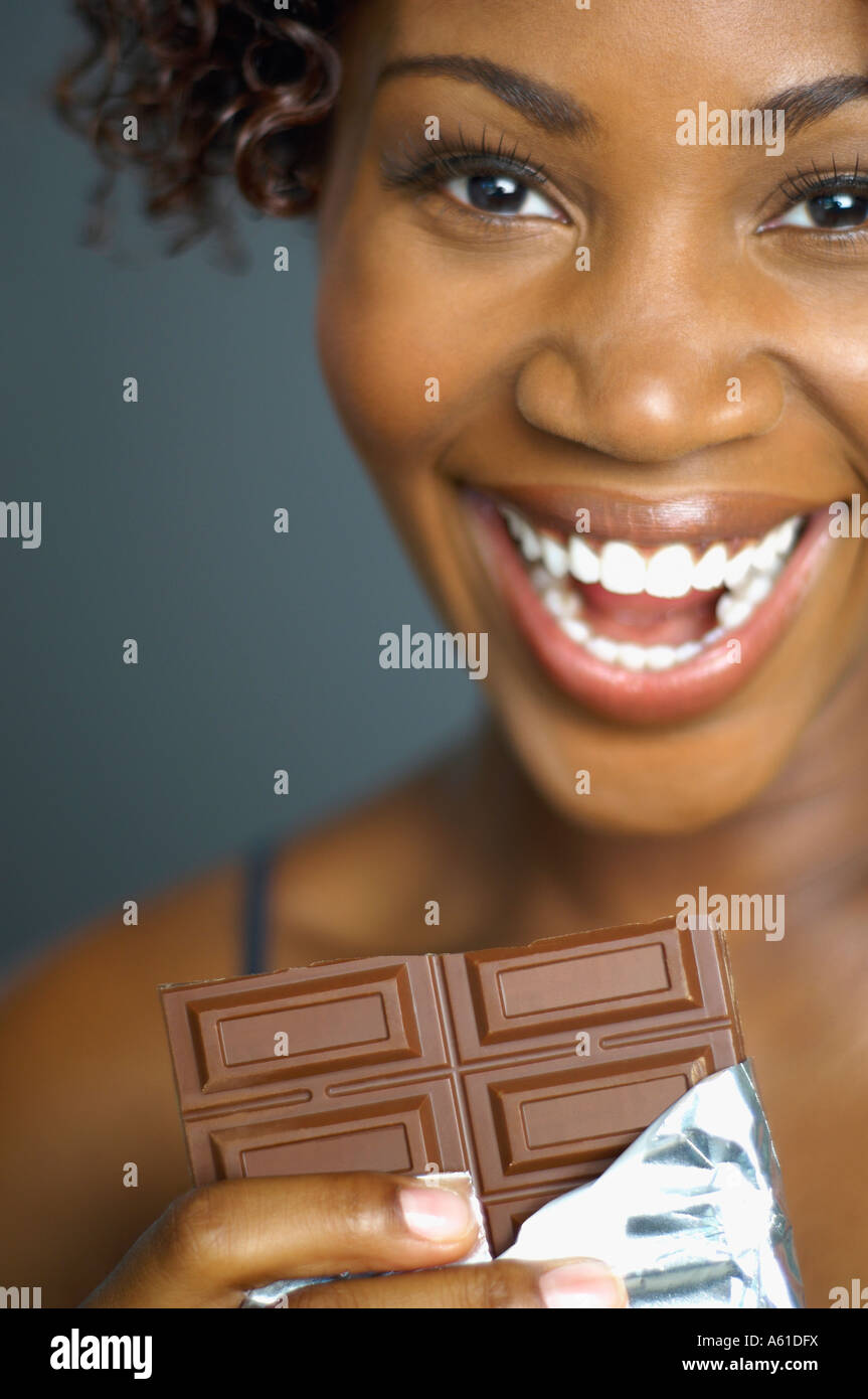 African woman eating chocolate bar Stock Photo