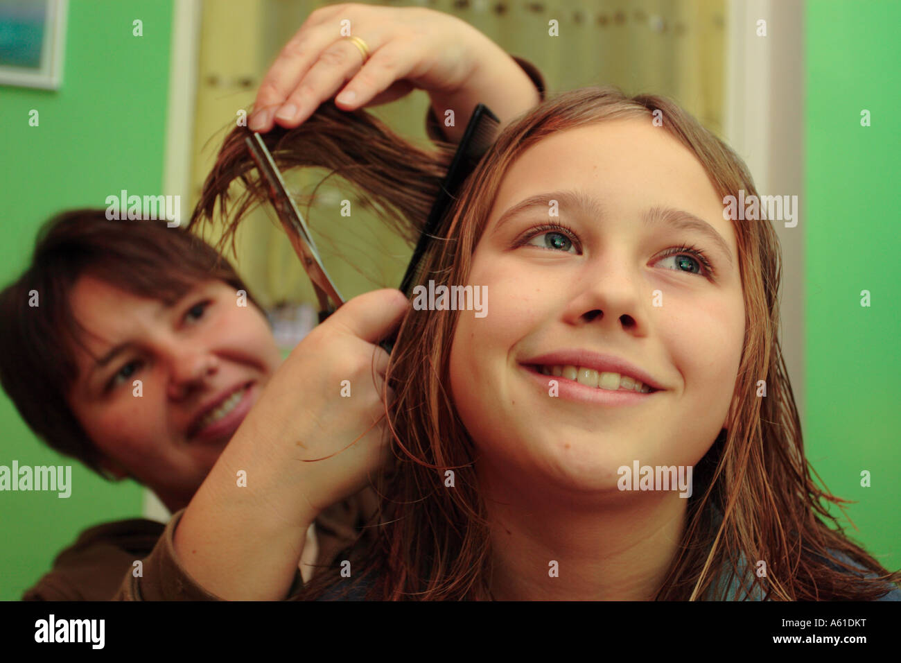 Young girl having her hair cut by her mother at home Stock Photo - Alamy