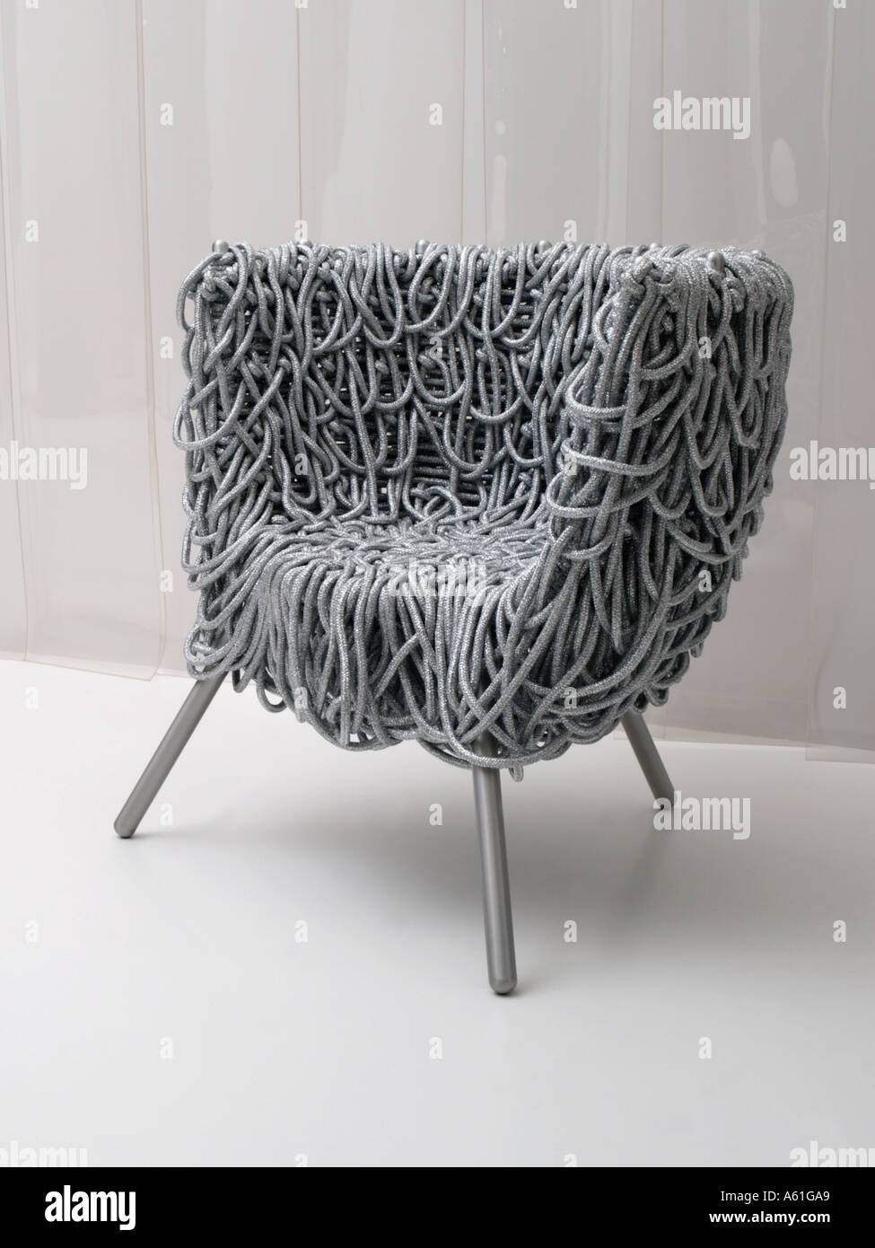 Three legged silver colored designer chair made of draped rope Stock Photo