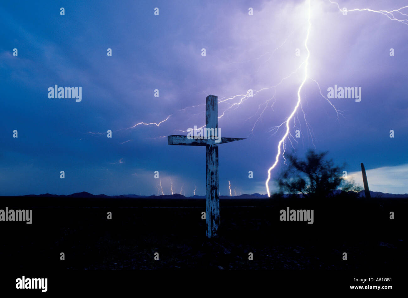 Huge lightning bolt crashes down close to a large wooden cross in southern Arizona on Native American land near Ajo, AZ. USA Stock Photo