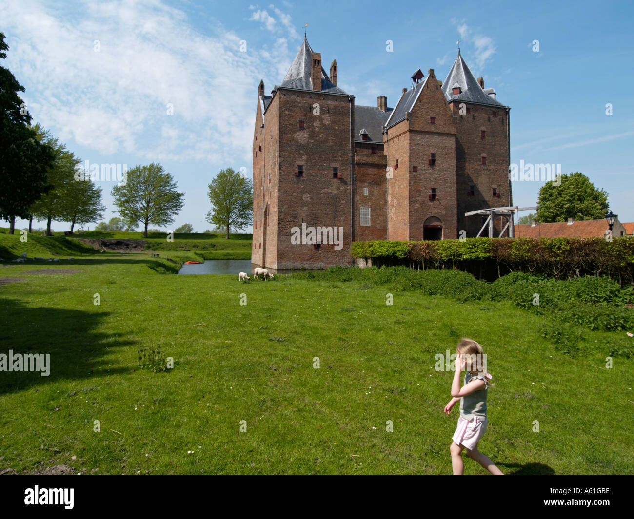 Little blond girl walking in the grass near castle Loevestein Woudrichem Noord Brabant the Netherlands Stock Photo