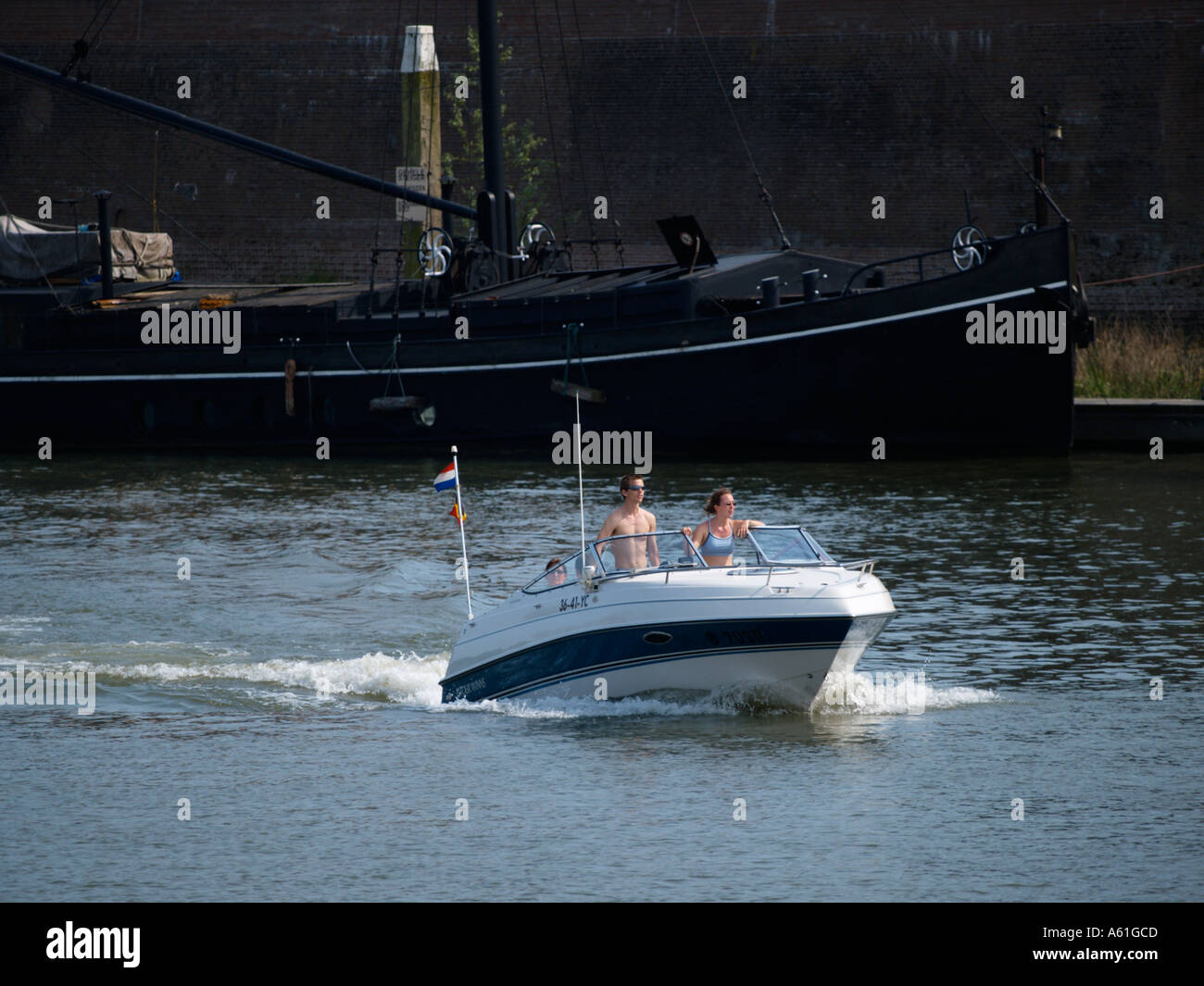 Speedboat cruising at low speed in the Woudrichem historic port Noord Brabant the Netherlands marina river Stock Photo